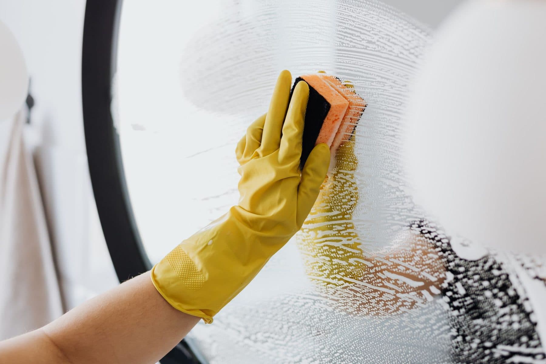 Gloved hands cleaning a bathroom mirror