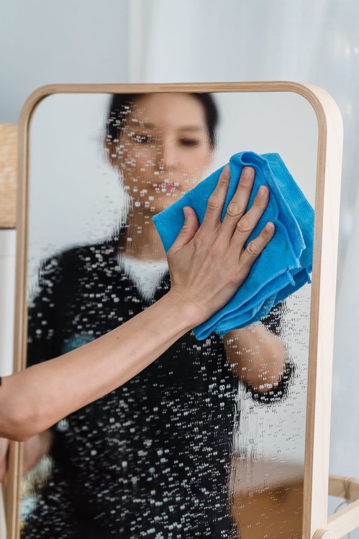 Cleaner wiping a mirror before guests arrive